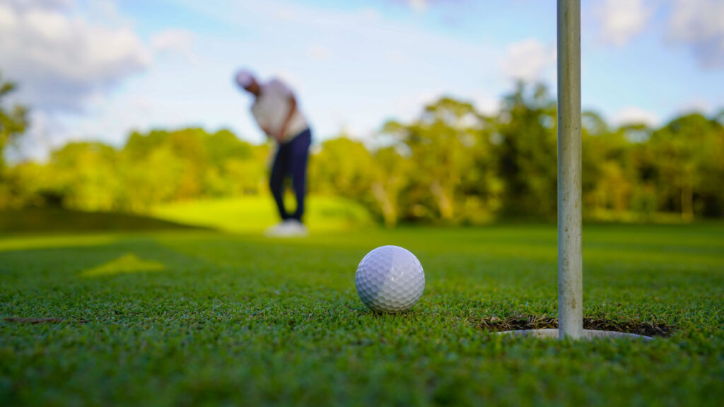 Golfers are putting golf in the evening golf course golf backglound. Golfer hitting golf ball. Sport holiday lifestyle Concept.